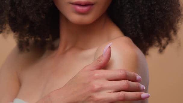アフリカ系アメリカ人女性モデル ベージュスタジオで微笑む美しい少女 完璧なきれいな滑らかな健康な皮の肩の保湿スキンケア クリームボディローション製品化粧品 — ストック動画