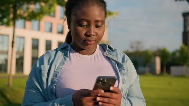驚くほど幸運なアフリカ系アメリカ人女性は 携帯電話アプリソーシャルメディアを使用して驚きの女性を驚かせました 優れたニュース 素晴らしいニュース 幸せな女性の勝利 スマートフォンで読む 素晴らしい情報を屋外で読む 都市で — ストック動画