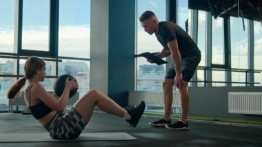 Spor salonundaki spor eğitmeni spor salonundaki spor eğitmeni spor salonundaki sporcu kadın sporcuyla beyaz kız spor topu ekipman erkek antrenörü antrenmanı yapıyor.