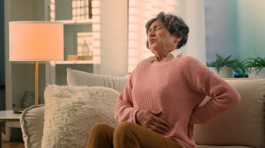 Beyaz, yaşlı bir kadın böbreklerinden acı çekerek yürümeye çalışıyor. Yaşlı bir kadın. Yaşlı, olgun, yaşlı bir kadın.