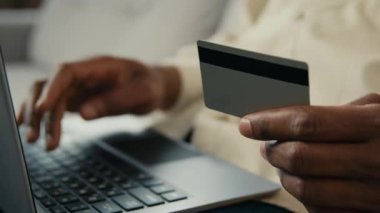 Yakın plan tanınmayan Afro-Amerikan iş adamı müşteri online ödeme yapıyor. Bilgisayarlı erkek müşteri, online mağaza e-bankacılık hizmetlerinde anında kolay ödeme yapıyor.
