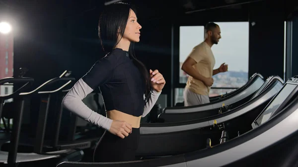 Sports people runners trainers running on treadmill in sport gym athletic man and woman run workout fit girl athlete sportswoman training cardio exercise run jogging in fitness club active lifestyle