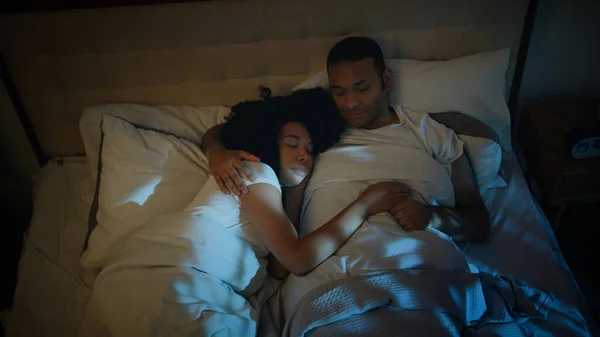 African American couple happy family boyfriend girlfriend wife husband woman man in love family sleeping hugging in cozy comfortable bed at dark home bedroom at night sleep together napping relaxing