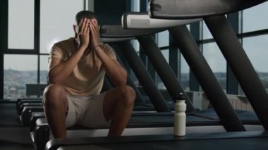 Yorgun Afrikalı Amerikalı sporcu, spor şişesinden su içiyor terli erkek koşucu spor salonunda protein içiyor koşu bandında egzersiz yaptıktan sonra vücut tazeleme susuzluğu çekiyor.