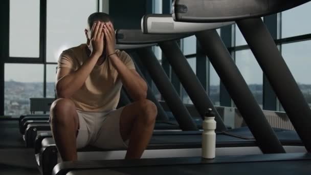 疲惫不堪的非洲裔美国运动员男子运动员在健身房休息时 在跑步机上进行了有氧运动 口渴后 从运动瓶中喝水 精疲力竭 汗流浃背的男子运动员在健身房休息时喝蛋白质 — 图库视频影像
