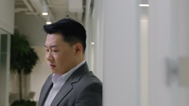 移動ショット 疲れ切ったアジアの中国の中年男性の頭痛張力使用携帯電話 オフィスの廊下のロビーの男性韓国ビジネスマン ビジネス 雇用主 Ceo 損失の携帯電話の失敗の敗北 — ストック動画
