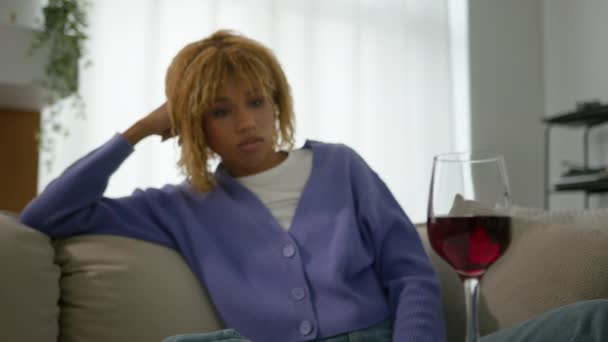 悲しい孤独な民族的アフリカ系アメリカ人の少女ペンシルベニアの思慮深い女性は 赤ワインのアルコール依存症のリラックスうつ病のガラスを見てリビングルームソファーでリラックスして自宅でリラックス考えている — ストック動画