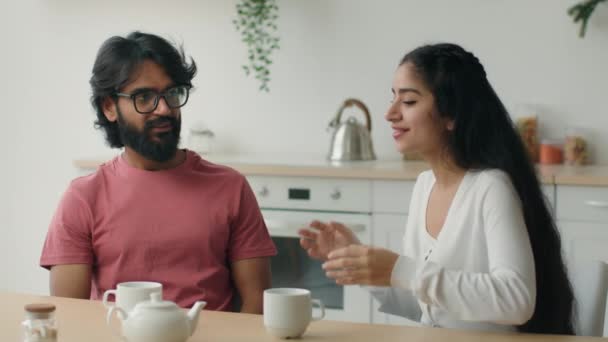 快乐的多种族夫妇在家里喝茶厨房里友好地聊天阿拉伯男人听有趣的故事无忧无虑的交谈印度女人讲故事浪漫的约会朋友友谊 — 图库视频影像
