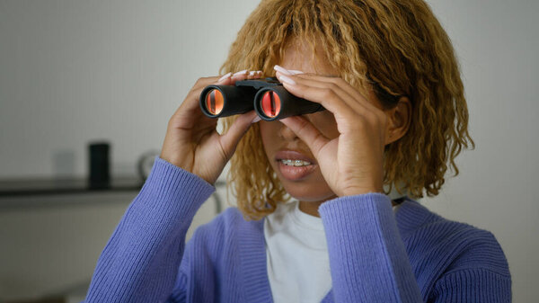 Афроамериканка любопытная женщина этническая девушка подозрительная шпионка дома, смотрит в бинокль шпионский взгляд глядя в окно тайное наблюдение созерцая ревность подруги