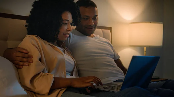 幸せな家族の男と女性のガールフレンドとボーイフレンド アフリカ系アメリカ人のカップル ベッドの夜の家で夜のショッピング ラップトップと一緒に商品を選ぶ オンライン インターネット購入 話し合い コンピュータを使用して — ストック写真