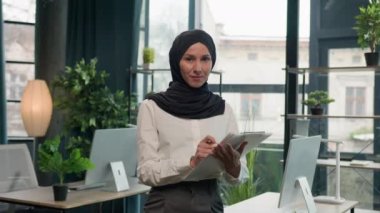 Mutlu Müslüman Müslüman kadın tesettürlü Arap kız, kağıt tabletle İK müdürü, notlar yaz, not tableti imzala, yapılacaklar listesi iş görüşleri başarılı iş kadını iş akışı planlama
