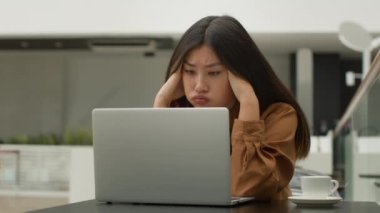 Stresli Asyalı kadın ofis çalışanı Çinli Çinli Japon kız serbest çalışıyor kafeteryada dizüstü bilgisayarla çalışıyor iş stresi işi hatası web sitesinde hata