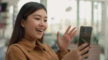 Mutlu Asyalı kadın merhaba diyor alışveriş merkezi kadın blogcusu Çinli Koreli Japon iş kadını cep telefonu kullanıyor cep telefonu bağlantısı kuruyor cep telefonu konuşmaları yapıyor.