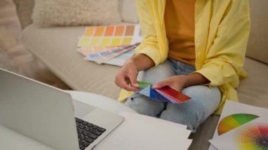Bilinmeyen kadın ellerinde renk paleti rehberi grafik tasarımcı kız malzeme renk tonu numunesi seçiyor ev tasarımı projesi için dizüstü bilgisayardan çok renkli gölgeler seçiyor renkli kumaş örnekleri tutuyor