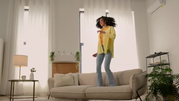 面白い アフリカ系アメリカ人女性 幸せな女の子 ホーム ダンス ジャンプ 楽しい馬鹿げた喜び テスト 快適な柔らかいソファー アパートダンス — ストック動画