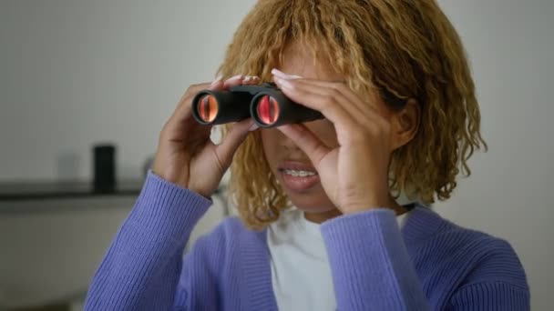非洲裔美国人好奇的女人少数民族女孩在家里可疑的间谍女人通过双筒望远镜窥视凝视着窗外的秘密观察所想嫉妒的女朋友 — 图库视频影像