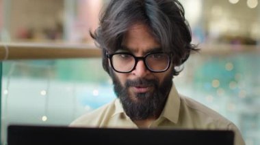 Heyecanlı erkek yönetici Hintli sakallı, gözlüklü girişimci dizüstü bilgisayar başarısından çok memnun. Mutlu Arap işadamı bilgisayar okuyarak iyi haberler alarak iş başarısını kutluyor.