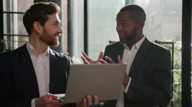 İki farklı etnik çeşitlilikte heyecanlı Kafkasyalı ve Afrikalı beyaz iş adamı iş arkadaşları iş başarısını kutluyor iş arkadaşlarıyla keyifli sohbetler dizüstü bilgisayarla iyi sonuçlar.