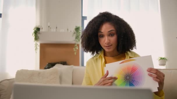 非裔美国女性装饰设计师讨论家庭内部项目笔记本电脑视频通话在线会议展示彩色彩虹色调调色板的纸样展示彩色光谱 — 图库视频影像