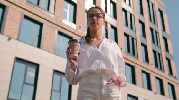 成功した自信を持った女性の女子学生は 街頭に紙コップホットドリンクを保持し 平和的な女性のビジネスマンは 朝をリラックスして休むオフィスビルの近くでコーヒーを破る — ストック動画