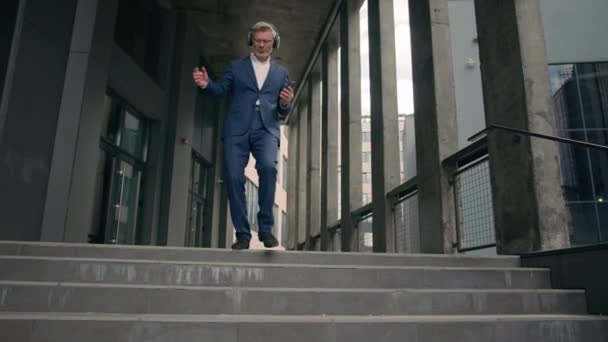 老实人白种人老实人白种人员工资深商人工人拿着耳机听音乐手握着手机跳舞走下楼梯间在城市快乐快乐的心情成功跳跃 — 图库视频影像