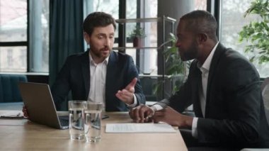 Çeşitli çok ırklı Afrikalı Amerikalı ve Kafkasyalı iş arkadaşları iş adamları finans ajanları ofis bilgisayarlarıyla başlatılan iş projelerini evrak evraklarıyla tartıştılar.