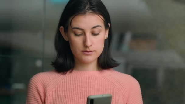 スマートフォンサーフィンソーシャルメディアチャットモバイルチャットを使用して深刻な白人静かな女性は 屋内でニューステキストメッセージをチェックします オフィスでスマートフォン技術を閲覧する女性少女ビジネスマンユーザー — ストック動画