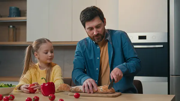 快乐的家庭厨房做饭白种人爸爸切面包和可爱的小女儿说话小女孩教切面包面包面包早餐健康的蔬菜沙拉一起说话 — 图库照片
