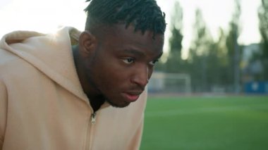 Düşük başlangıç pozisyonunda Afrikalı Amerikalı sporcu yarış koşucusu olmaya hazırlanıyor. Açık hava stadyumunda koşmaya başlıyor. Erkek triatlet sporcusu başlangıç çizgisinde koşu antrenman maratonu yapıyor.