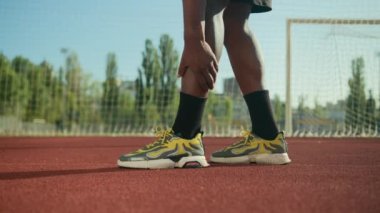Kırpılmış erkek bacakları, Afro-Amerikalı tanınmayan erkek sporcu atlet, spor ayakkabılı futbolcu, masaj yapan, bacak ağrısı, diz ağrısı, kramp, spor travması, futbol antrenmanı.