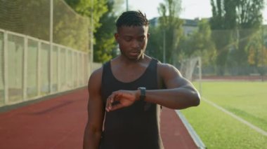 Afrikalı Amerikalı koşucu koşucu sporcu kaslı sporcu açık havada atletizm eğitimi alıyor. Zeki bant kullanıyor. Kalp atış hızını kontrol ediyor.