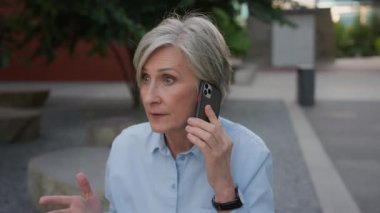 Kızgın, deli, üst düzey iş kadını, beyaz, yaşlı kadın, konuşan, cep telefonlu, hoşnutsuz iş kadını, şehir caddesinde konuşan, akıllı telefon çatışması, dışarıda bağırış çağırış kavgası.
