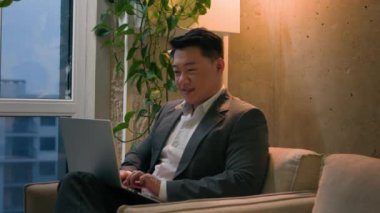 Koreli Çinli iş adamı, modern ofis gökdeleninde dizüstü bilgisayarla çalışan, erkek, işveren, işveren, yönetici, yönetici, uzaktan kumanda, projeyi tamamladı, bilgisayardan gülümseme.