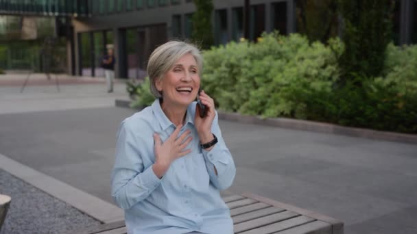 幸せな感情的なコーカサス 古い女性のビジネスウーマン 興奮する女性 都市のスマートフォン通話の携帯電話を話す 楽しい遠隔会話 成熟したビジネス 女性の世話 — ストック動画