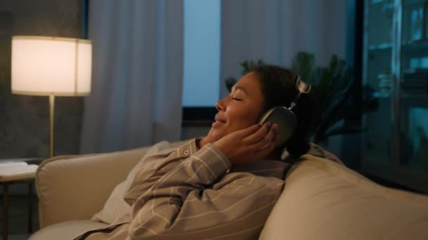 Entspannte Afroamerikanerin Mit Kopfhörer Fallen Auf Bequemes Gemütliches Sofa Abend — Stockvideo