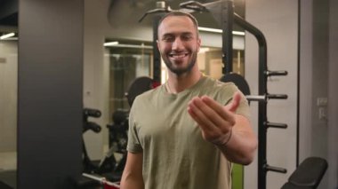 Gülümseyen mutlu etnik fitness antrenörü kaslı güçlü gülümseme Afrikalı Amerikalı adam hoş geldin jest elini buraya davet et sporcu sporcu sporcu sporcu sporcu spor kulübüne davet et