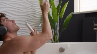 Beyaz adam banyoda köpüklü, neşeli, kaygısız, kulaklıklı, müzik dinleyen duş jeli şampuanında şarkı söyleyen, sabah banyosunda banyoda yıkanan sesi dinleyen adamla rahatlıyor.