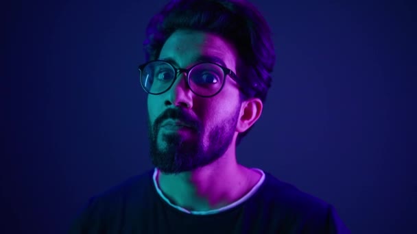 ポートレートを閉じる ネオンの紫外線背景 インドの男 開発者コーダー スマートハッカー 賢いコーディング コンピューター エンジニア ジェスチャー 考える — ストック動画
