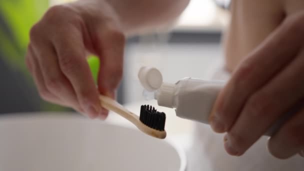 紧紧抓住男性双手无法辨认的男人把医用洁白牙膏压在生态竹子牙刷上准备刷牙清洁洗牙口腔卫生早上程序习惯 — 图库视频影像