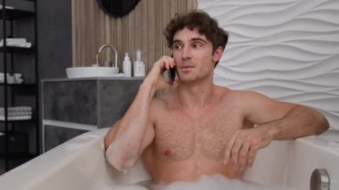 Beyaz, çıplak erkek, küvette sabunlu köpükle dinleniyor, banyoda dinleniyor, akıllı telefon görüşmeleri yapıyor, cep telefonu görüşmeleri yapıyor, küvette temizlik spa 'sında çamaşır yıkamayı konuşuyor.