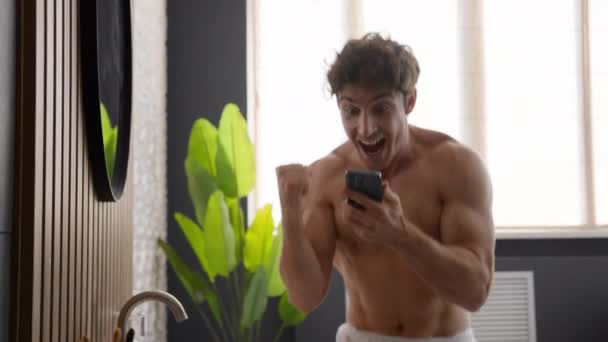 白种人赤身裸体男人在浴室男士们在浴室里洗澡早上的美容程序看手机庆祝手机实现了在线胜利智能手机赢得了胜利手机实现了快乐短信提供舞蹈 — 图库视频影像