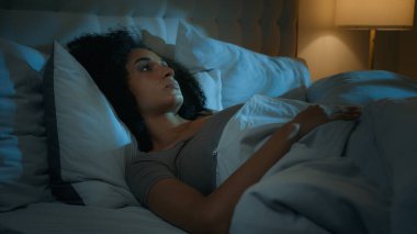 Gürültücü komşular rahatsız edici Afro-Amerikan kadın gece yatağında uzanan karanlık yatak odasında uykusuzluk çeken uykusuz, öfkeli kız gürültüyle kulaklarını yastıkla kapatarak uyumaya çalışıyor.