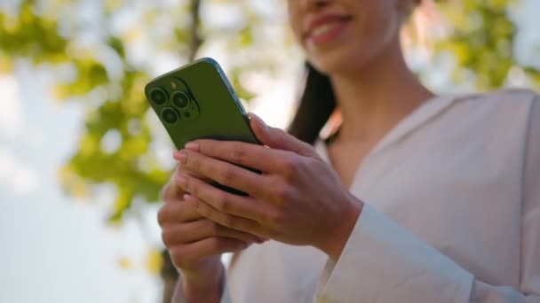モバイルアプリのチャットを使用してスマートフォンで電子メールをチェックするSmsメッセージを送信するソーシャルネットワークを閲覧している日光の笑顔の女性のスマートフォンで屋外で携帯電話を持っているクローズアップ女性 — ストック動画