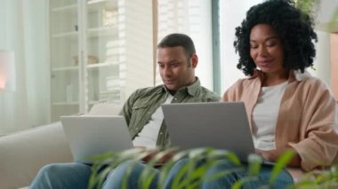 Çok ırklı, Afrikalı, Latin kökenli iş adamları laptoplarla oynuyorlar bilgisayarlara bakıyorlar, internetten alışveriş yapıyorlar aşık çift ve erkek gülümsüyor modern teknolojileri kullanıyorlar.