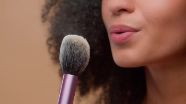 化妆品美容美发概念特写剪影无法辨认的非裔美国女人不明模特拿着刷子吹去灰尘在米色工作室的背景护肤 — 图库视频影像