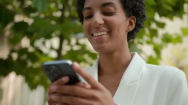 Mutlu gülümseyen Afrikalı Amerikalı iş kadını sosyal medyada cep telefonu uygulaması ile sohbet ediyor. Şehir iş kadınlarında taksi çağıran kızla buluşmayı bekliyor. Parkta akıllı telefon sohbetini internet üzerinden yapıyor.