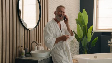 Mutlu gülümseyen Kafkasyalı emekli yaşlı adam akıllı telefon dostça konuşabiliyor. Uzaktan sipariş verebiliyor. Cep telefonu konuşabiliyor.