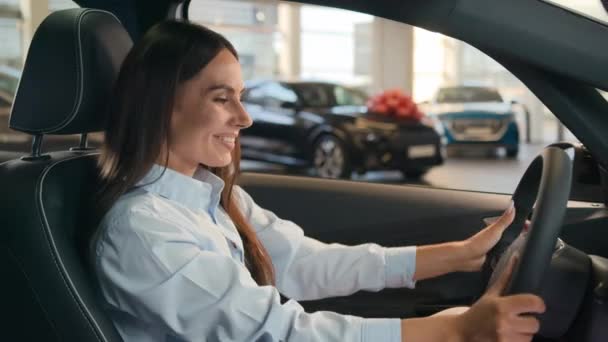 ハッピーコーカサス成功したビジネスウーマン喜びの女性は 自動車ショップのレンタルサービスディーラーで新しい車に座って 自動車購入の高級モダン購入車の女性テストドライブをレンタルすることを決定します — ストック動画