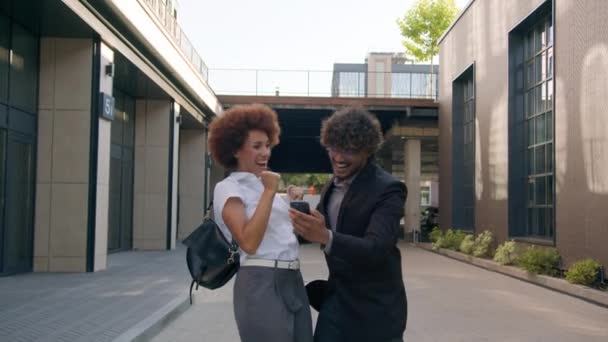 アフリカ系アメリカ人女性ビジネスマンと都市の同僚アラビアのビジネスマンでビジネス多種多様な同僚は スマートフォン勝利携帯電話良い成功の達成は 高い5を与える — ストック動画