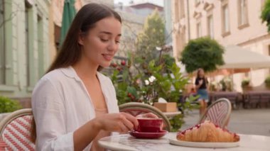 Gülümseyen Avrupalı bayan turist kahvaltının tadını çıkarıyor Kafkasyalı kadın Aroma kokan kafeteryada sıcak kahve kruvasanının tadını çıkarıyor. Haftasonu restoranda rahatça dinleniyor.